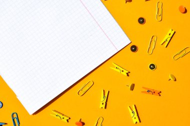 Not defterlerinden beyaz kare kağıt, ahşap renkli mandal, ataç, metin için kopya alanı, okula dönüş konsepti, kırtasiye ofis malzemeleri, üst görünüm