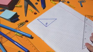 Öğrenci el çizimi üçgeni ve kağıt not defterinde geometri üçgeni çözmek, ödev matematiği, okula dönmek, okul malzemeleri, evde çalışmak.