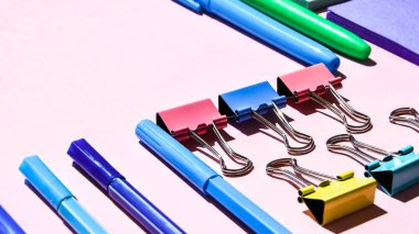 Pembe arka planda farklı ofis ya da okul malzemeleri. Metin, kalem kağıdı, ataç, etiket ve mandal için boşluk kopyala