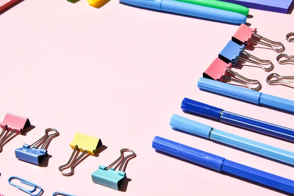 Different office or school supplies on pink background. Copy space for text, pencil paper clip stickers markers and clothespin