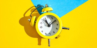 Mavi ve sarı arka planda sarı alarmlı saat seçici odaklı, metin için kopyalama alanı zaman kavramı, gecikme, sabah kalkışı, kararlaştırılan toplantı, ikiz zilli klasik alarm saati, dinlenme saatleri günaydın