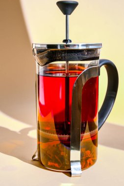 Bitkilerle demlenmiş baharatlı meyve çayı, gül çiçekleri, sarı arkaplanda metin için fotokopi alanı olan sıcak sağlıklı içecek, Hibiscus çayı, çiçek ve kuru çiçek, sıcak çay ile cam çaydanlık.