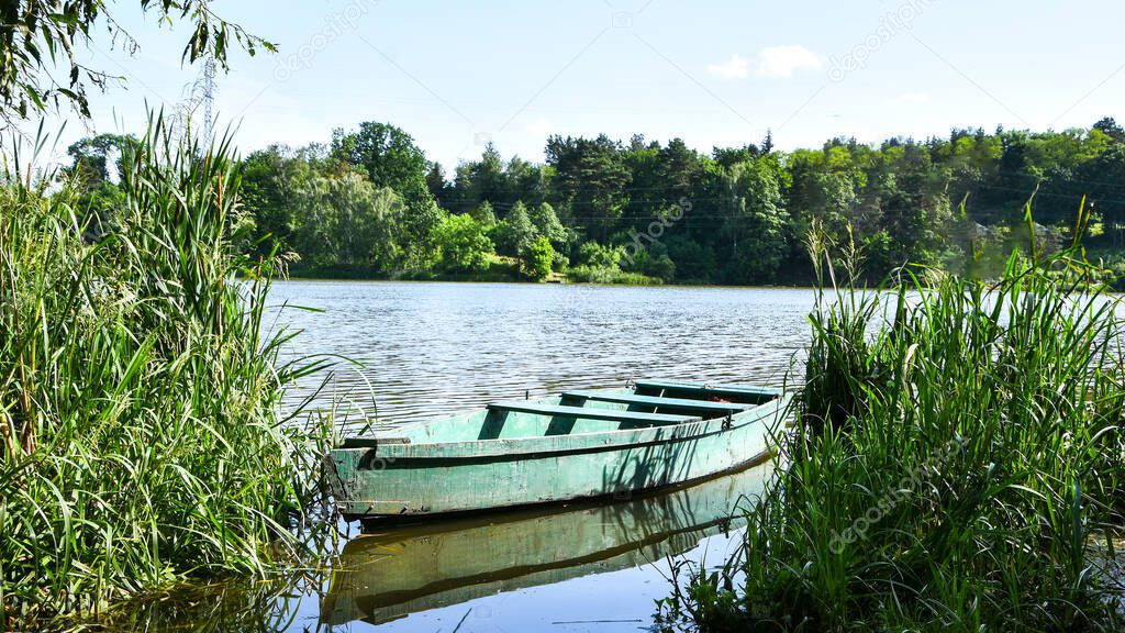 Wooden pier or jetty and a boat on lake sunset and sky reflection water. Boats Moored In Lake By Plants Against Clear Sky. Summer leisure