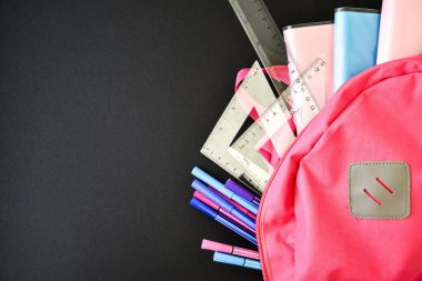 Tahta zeminde okul gereçleri olan pembe sırt çantası, yazı için boşluk kopyalama, okula dönüş, cetvel kalem kitapları.