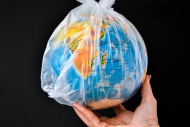 Küre şeklinde bir top plastik bir torbanın içinde. Dünyanın plastik kirliliği kavramı. Dünya Çevre Günü kavramı. Oyuncak dünya küresi beyaz plastik torba içinde. Uzayı metin için kopyala. Dünyayı Kaydet