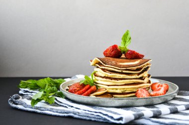 Geleneksel Krep ve Çilekli Küçük Krep Gevreği ve Karanlık Arkaplanda Nane Yaprakları ile Tabak. Moda yemekler. Mini mısır gevreği krepleri.