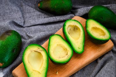 Taze avokado, olgun avokado ve avokadoyu kemikle keser. Tahta bir sandıkta olgun sonbahar armutları