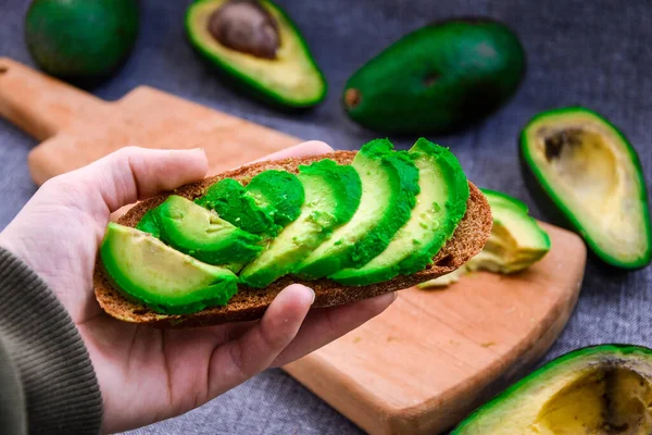 Gezond Ontbijt Vrouwelijke Hand Met Avocado Toast Groene Biologische Avocado — Stockfoto