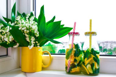 Limonata, limon ve salatalık, pencere kenarındaki nane yaprakları, yaz ferahlatıcı detoks içecekleri, seçici odak, vadideki zambak çiçeği.