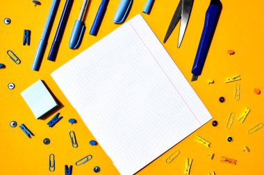 Not defterlerinden beyaz kare kağıt, ahşap renkli mandal, ataç, metin için kopya alanı, okula dönüş konsepti, kırtasiye ofis malzemeleri, üst görünüm