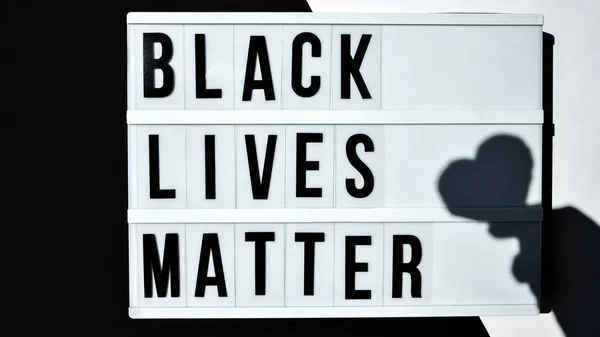 BLACK LIVES MATTER text with deep shadows of heart on a black and white background. Protest against the end of racism, anti-racism, equality. Poster on violation of human rights