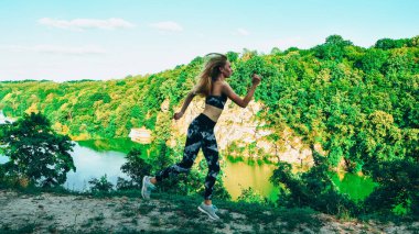 Dağlarda koşan bir kadın, otlakta koşan genç bir fitness kadını. Açık hava sporu.