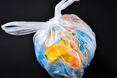 Küre şeklinde bir top plastik bir torbanın içinde. Dünyanın plastik kirliliği kavramı. Dünya Çevre Günü kavramı. Oyuncak dünya küresi beyaz plastik torba içinde. Uzayı metin için kopyala. Dünyayı Kaydet