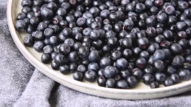 Ağır çekimde dönen yaban mersinlerini kaseye koy. Seçici odaklanma. Yabanmersini dönüşümlü arka plan. Taze ve olgun organik yabanmersini rotası. Diyet, diyet, sağlıklı vejetaryen yemekleri. Organik