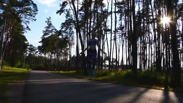 Silueta de cámara lenta del deporte de la mujer y la cuerda saltando con puesta de sol en el bosque, los rayos del sol árboles. atleta saltando sobre saltar la cuerda al aire libre — Vídeos de Stock