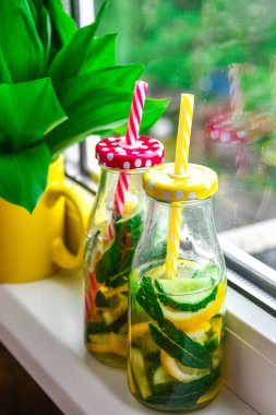 Limonata, limon ve salatalık, pencere kenarındaki nane yaprakları, yaz ferahlatıcı detoks içecekleri, seçici odak, vadideki zambak çiçeği.