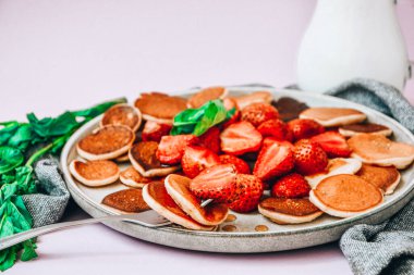 Geleneksel Krep ve Çilekli Küçük Krep Gevreği ve Karanlık Arkaplanda Nane Yaprakları ile Tabak. Moda yemekler. Mini mısır gevreği krepleri.