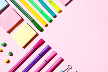 Pembe arka planda farklı ofis ya da okul malzemeleri. Metin, kalem kağıdı, ataç, etiket ve mandal için boşluk kopyala