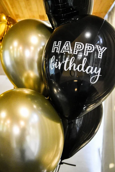 Birthday Party Balloons, golden and black balloons. The photo zone is decorated with black and yellow balloons . round golden balloon. stylish party with balloons. Happy birthday text on balloon