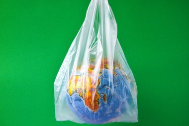 Küre şeklinde bir top plastik bir torbanın içinde. Dünyanın plastik kirliliği kavramı. Dünya Çevre Günü kavramı. Oyuncak dünya küresi beyaz plastik torba içinde. Uzayı metin için kopyala. Dünyayı Kaydet