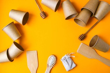 Çevre dostu tek kullanımlık kağıt bardaklar, ahşap mutfak aletleri, sarı arka planda saç fırçası pamuk torbası. Uzayı kopyala Eko fast food. Plastiksiz. Sıfır kayıp. Çevre dostu materyal