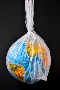 Küre şeklinde bir top plastik bir torbanın içinde. Dünyanın plastik kirliliği kavramı. Dünya Çevre Günü kavramı. Oyuncak dünya küresi beyaz plastik torba içinde. Uzayı metin için kopyala. Dünyayı Kaydet