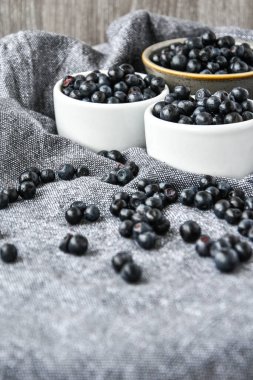 Mutfak havlusuyla birlikte Tahta Masa üzerinde küçük beyaz bir kase organik yabanmersini. Uzayı kopyala Yaz meyvesi. Taze orman meyvesi.