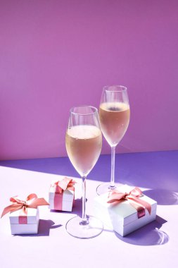 Renkli hediye kutularıyla dolu şampanya bardağı. Arka planda çözülmüş, metin için kopyalama alanı, parti kutlaması, alkol içeceği.