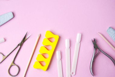 Pembe arka planda manikür ve pedikür aletleri, yukarıdan görüş. Manikür salonu afiş tasarım şablonu. Güzellik tedavisi konsepti. Metin için alanı kopyala