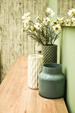 Ev dekorasyonu. Oturma odası parlak renklerde. Kahve masası, cam vazoda beyaz çiçekler. Rahat bir ev. Dikey fotoğraf