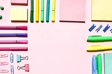 Pembe arka planda farklı ofis ya da okul malzemeleri. Metin, kalem kağıdı, ataç, etiket ve mandal için boşluk kopyala