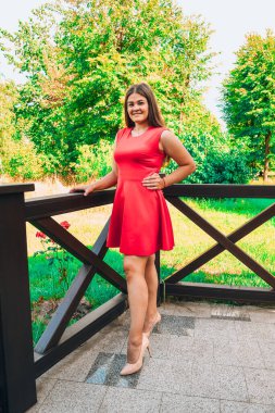 Uzun saçlı, kırmızı elbiseli güzel bir kız. Etkileyici, moda blogcusu fotoşopçu. Yüksek topuklu bir kız.