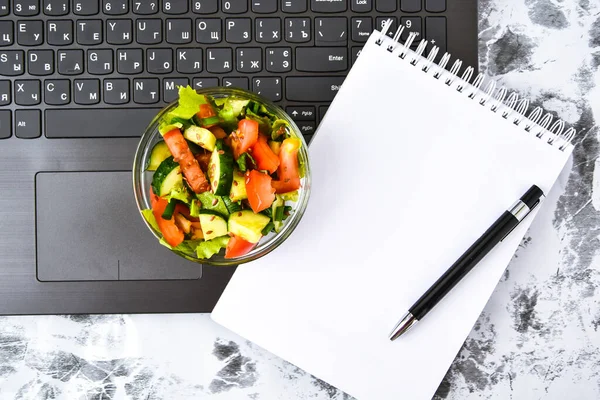 Healthy business lunch snack in office, vegetable salad, empty notebook with pen, copy space, low calorie diet