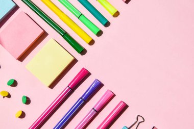 Pembe arka planda farklı ofis ya da okul malzemeleri. Metin, kalem kağıdı, ataç, etiket ve mandal için boşluk kopyala