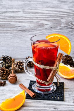 Baharatlı Noel şarabı ve ahşap kırsal arka planda portakal. Seçici odaklanma. Anason yıldızları ve tarçın çubukları. Noel konileri. Metin için alanı kopyala