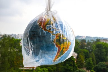 Küre şeklinde bir top plastik bir torbanın içinde. Dünyanın plastik kirliliği kavramı. Dünya Çevre Günü kavramı. Oyuncak dünya küresi beyaz plastik torba içinde. Uzayı metin için kopyala. Dünyayı Kaydet