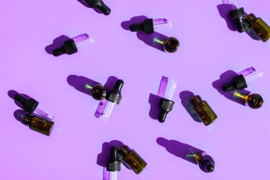 Renkli arka planda gerekli yağlardan oluşan şişeler, düz bir zemin. Kozmetik ürünler. Bırakan. Kahverengi kozmetik ve temel yağ şişeleri, aromaterapi, doğal kozmetik, fizyoterapi, konsept.