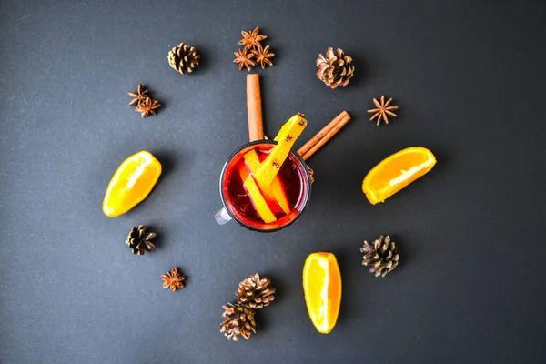 A clock in the form of spice for mulled wine on black background. Cinnamon sticks, anise stars, pine cones, slice of orange. Concept, creative work. Top view. Holiday atmosphere, Rustic style. The idea for creating greeting cards