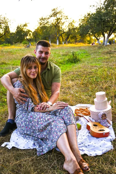 Felice giovane coppia rilassante e facendo un picnic nel parco. Tranquillo dolce coppia godendo la cena nel parco. Uomo e donna seduti sull'erba e abbracciati. — Foto Stock
