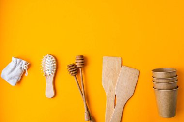 Çevre dostu tek kullanımlık kağıt bardaklar, ahşap mutfak aletleri, sarı arka planda saç fırçası pamuk torbası. Uzayı kopyala Eko fast food. Plastiksiz. Sıfır kayıp. Çevre dostu materyal