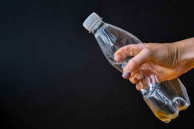 Elle tutulur plastik şişeler, konsept küresel ısınma, kullanım. Boş, ezilmiş su şişesi siyah arka planda izole edilmiş. Geri dönüşüm konsepti, plastiksiz. Boşluğu kopyala