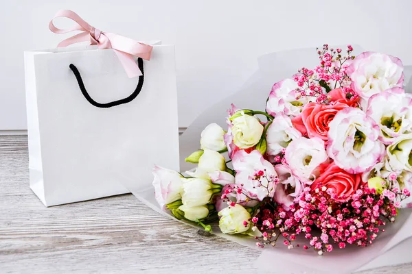 delivery service packing bouquet flowers pink white background gift shipping. Beautiful romantic composition with flowers. St. Valentines Day background. Eco bag present. Mockup copy space. Holiday concept