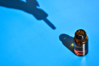 Mavi arka planda koyu gölgesi olan göz damlası şişesi. Modern yaratıcı minimalizm kavramı. Uzayı kopyala Serum teni