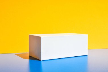 Beyaz kutu. Uyuşturucu kutusu maketi. Modelleme. Uzayı kopyala Sarı ve mavi minimalizm izometrik arka plan. Sert ışık. Gölgeler