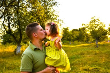 Mutlu bir baba ve küçük kızı güneşli bir arazide birlikte vakit geçiriyorlar. Baba kucaklar ve küçük kızı öper. Önce aile sevgisi..