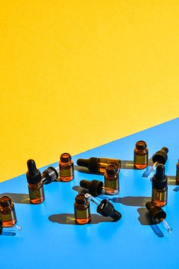Sarı ve mavi arka planda koyu gölgeli göz damlası şişeleri. Modern yaratıcı minimalizm kavramı. Boşluğu kopyala