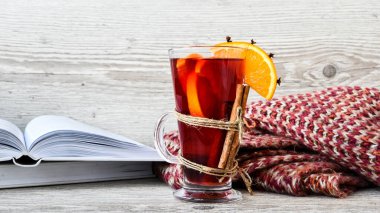 Sıcak şarap, ahşap arka planda baharatlar olan sıcak noel içeceği. Portakal dilimi, tarçın çubukları, kitaplar ve kazak. Noel sabahı. Tatil atmosferi, taşra tarzı. Tebrik kartı yapma fikri. Sonbahar içeceği