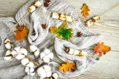 Sonbahar çerçevesi güz yaprakları, marşmelov, fındık, tarçın, pamuklu kazak. Ahşap arka planda üst manzara. Sonbahar kompozisyonu. Şükran Günü için süs