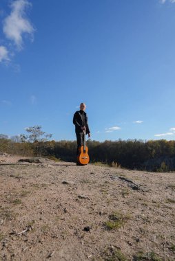 Güzel sarışın adam akustik gitar çalıyor ve şarkı söylüyor güneşli bir sonbahar gününde dışarıda eğleniyor. Sanatçı müzik aleti öğreniyor ve pratik yapıyor. Sonbahar mevsimsel havayı terk eder 