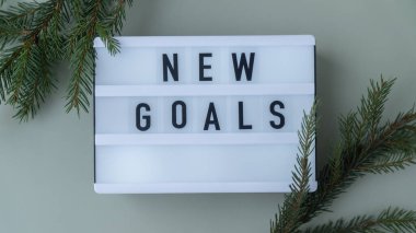 Renkli arka planda köknar dalları olan ilham verici mesajlar içeren ışık kutusu. Mutlu yıllar karar kavramını vaat eder. Kişisel gelişim ve kişisel gelişim